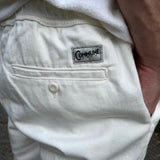 Détails du short écru Commune golf : poche arrière et étiquette avec logo commne golf