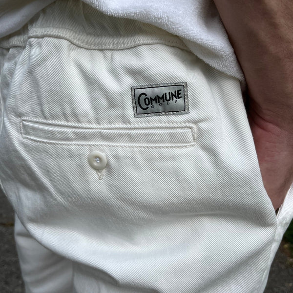 Détails du short écru Commune golf : poche arrière et étiquette avec logo commne golf